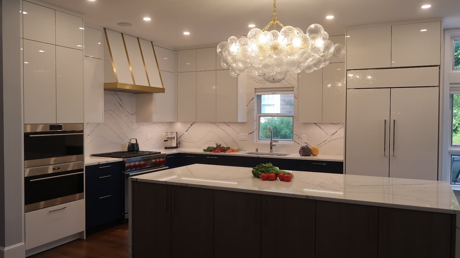 Transitional white kitchen with chandelier and dark island